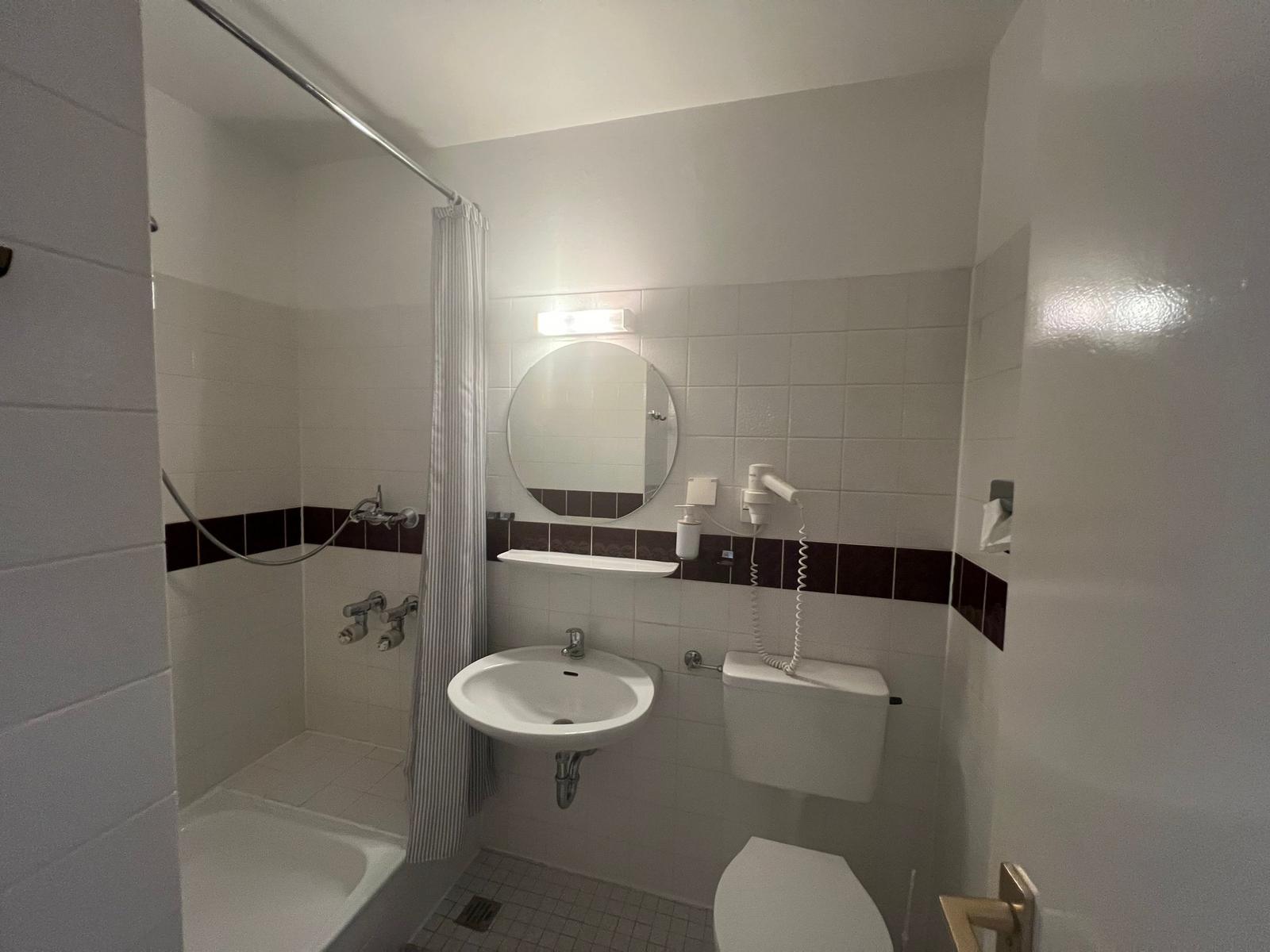 Badezimmer mit Dusche, Waschbecken und Toilette.