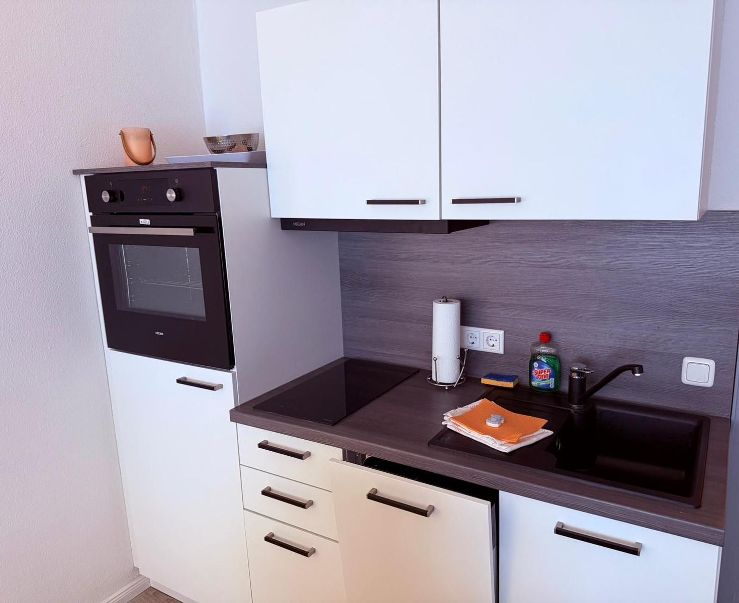 Küche mit Dunstabzug, Spüle, Herd und Backofen.