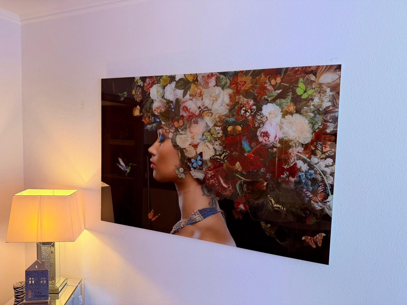 Ein Wandbild zeigt eine Frau mit Blumen und Schmetterlingen. Eine Lampe steht daneben.