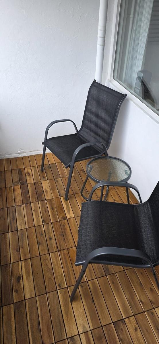 Terrasse mit zwei schwarzen Stühlen und einem runden Tisch auf Holzboden