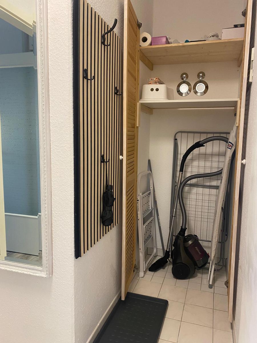 Eingangsbereich mit Garderobe, Staubsauger und Wäscheständer.