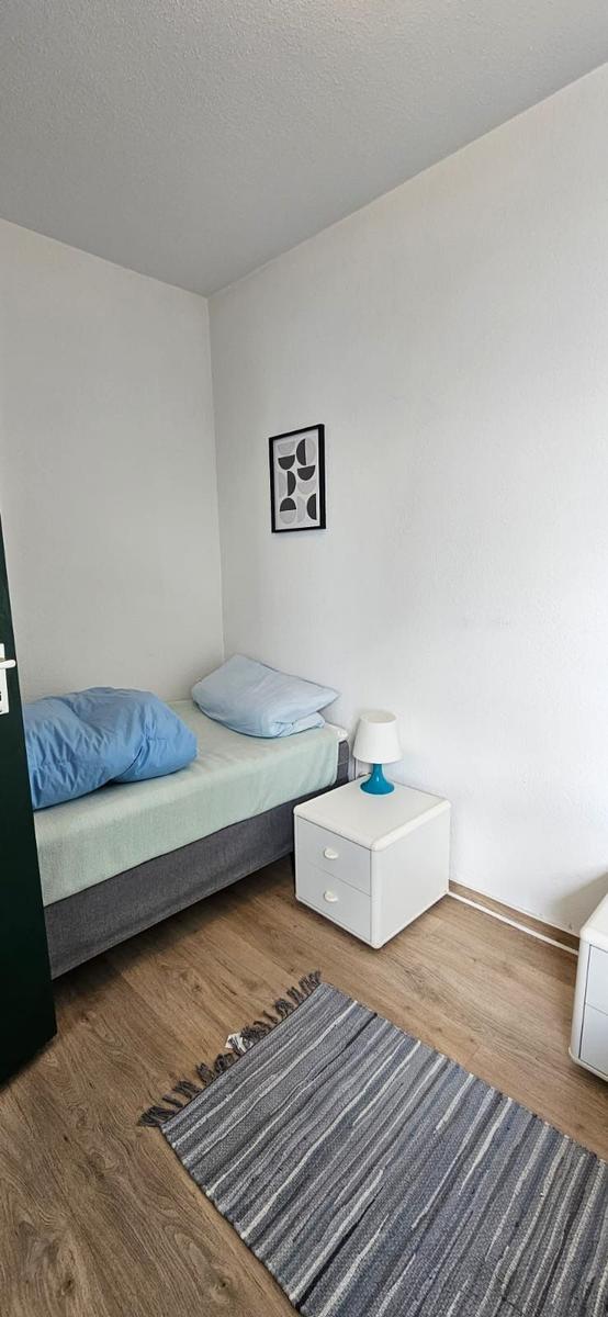 Ein Schlafzimmer mit einem Bett, Nachttisch und Teppich auf Holzboden.