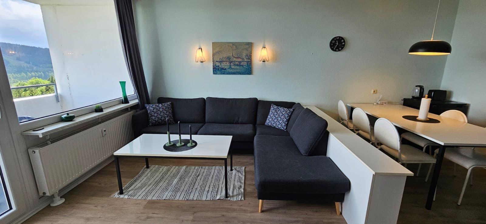 Wohn- und Essbereich mit Sofa, Tisch und Blick auf die Berge.