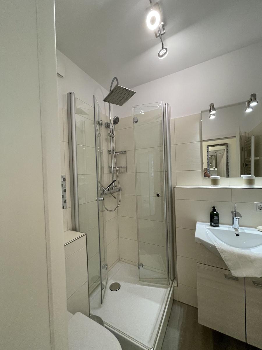 Badezimmer mit Duschkabine, Waschbecken und Spiegel