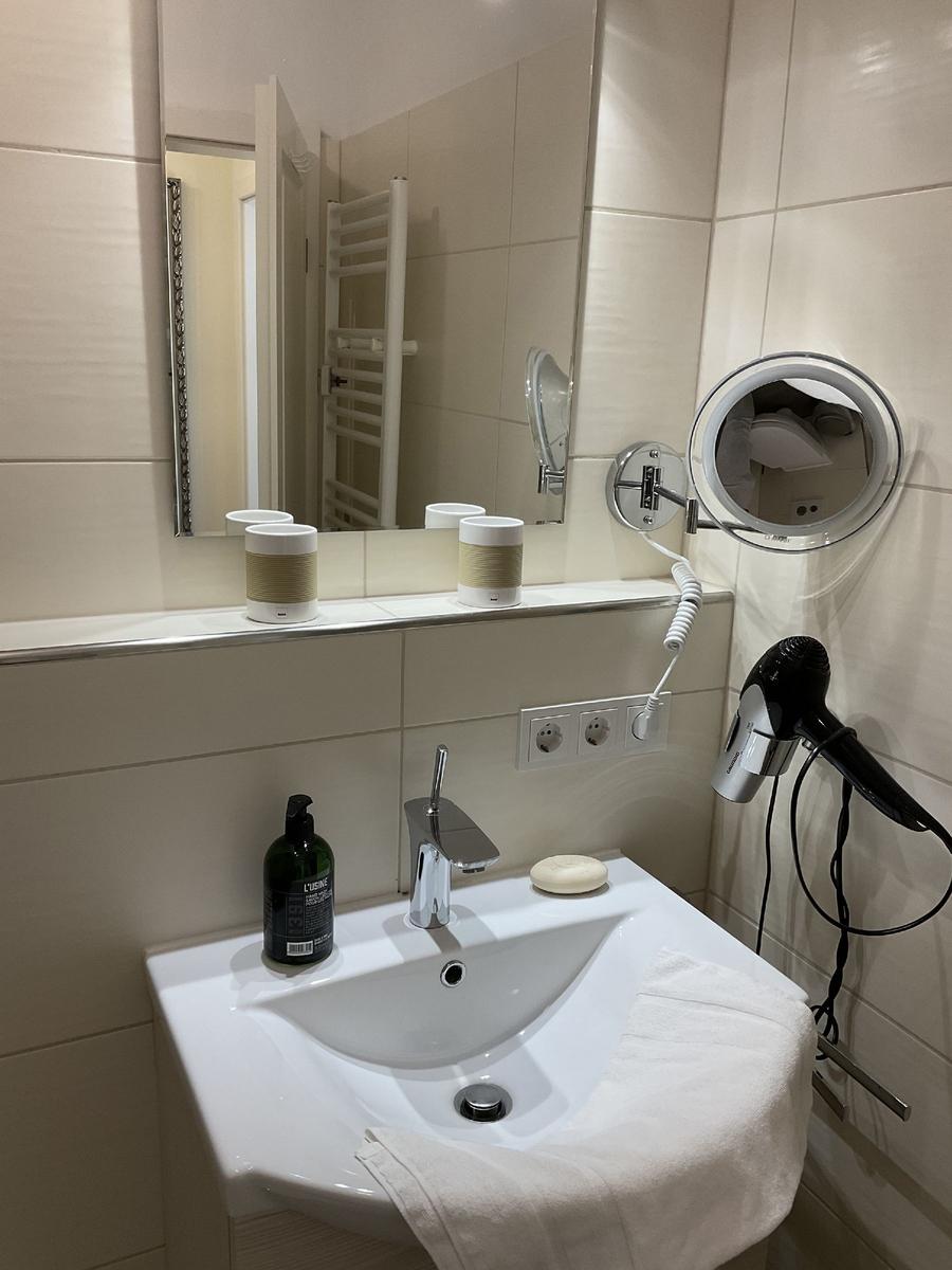 Waschbecken mit Spiegel, Handtuch und Haartrockner an der Wand.