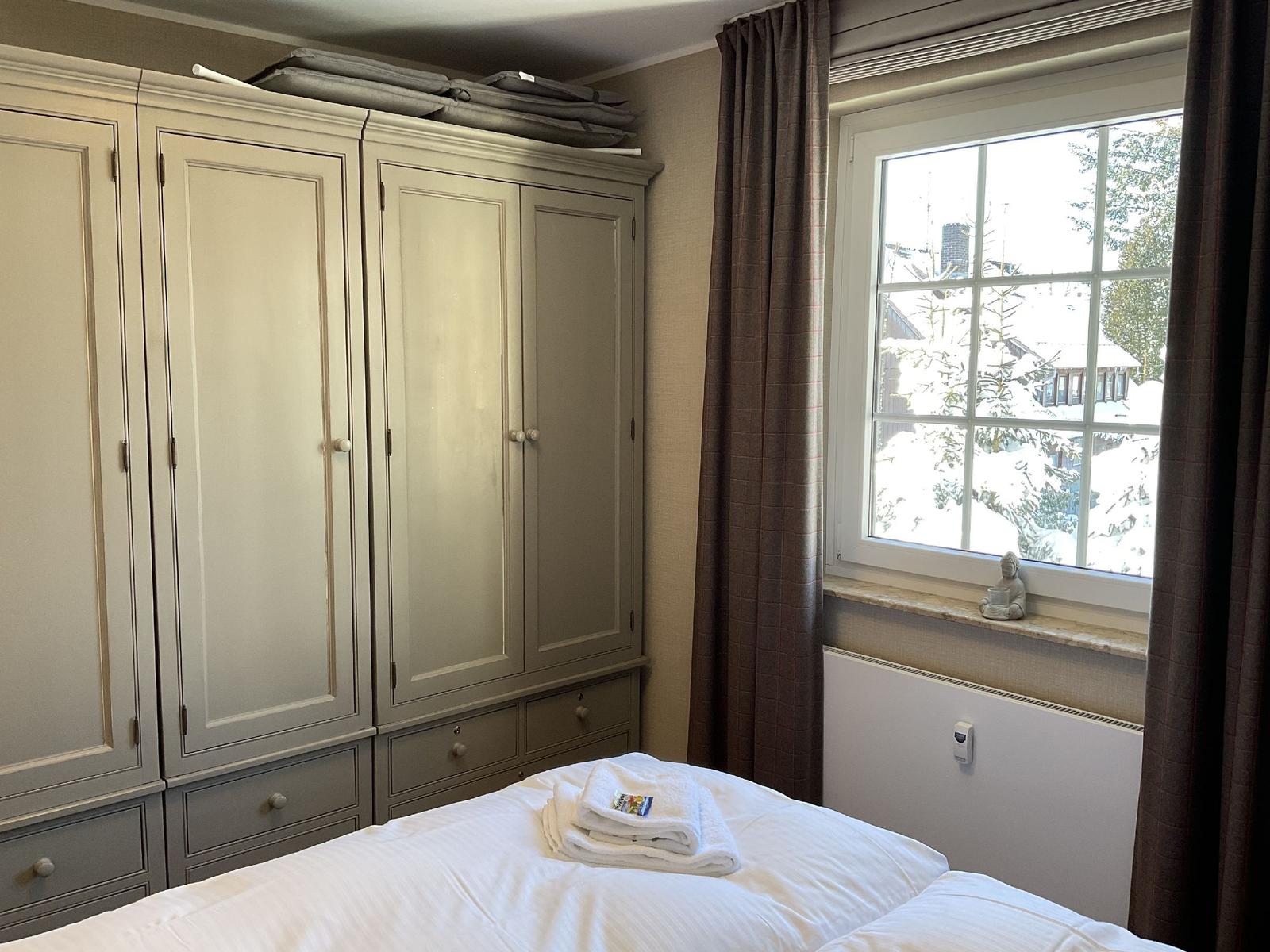 Schlafzimmer mit großem Schrank und Fensterblick auf schneebedeckte Bäume.