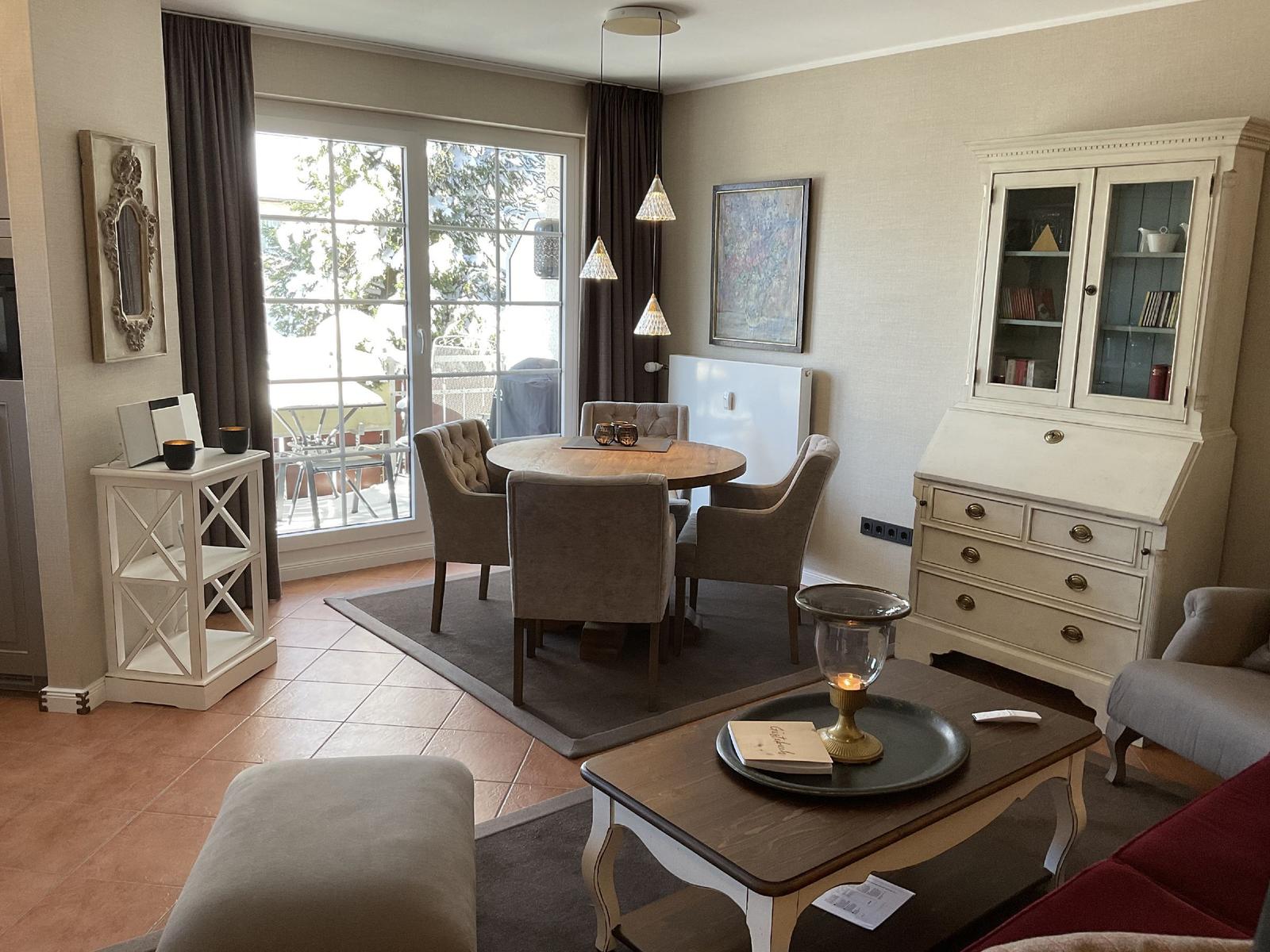 Essbereich mit runden Tisch, vier Stühlen und Glasfront zur Terrasse.