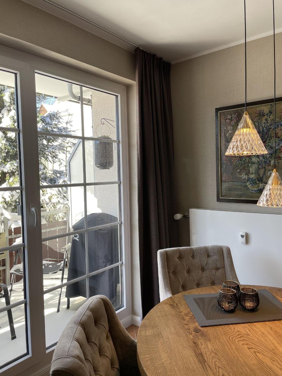 Essbereich mit Tisch, Stühlen und Blick auf verschneiten Balkon.