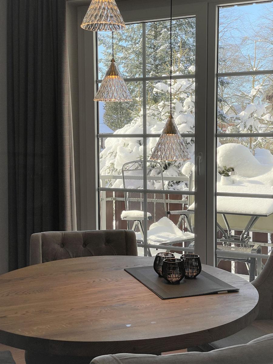 Runder Tisch mit Stühlen vor Fenster mit verschneitem Garten