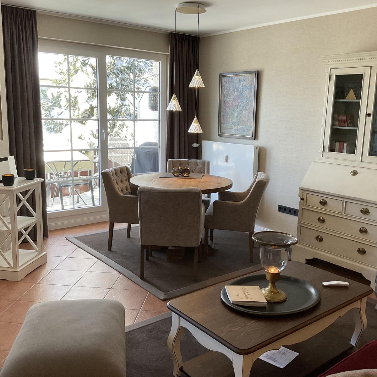 Esszimmer mit runden Tisch, vier Stühlen und Glasfront zur Terrasse.