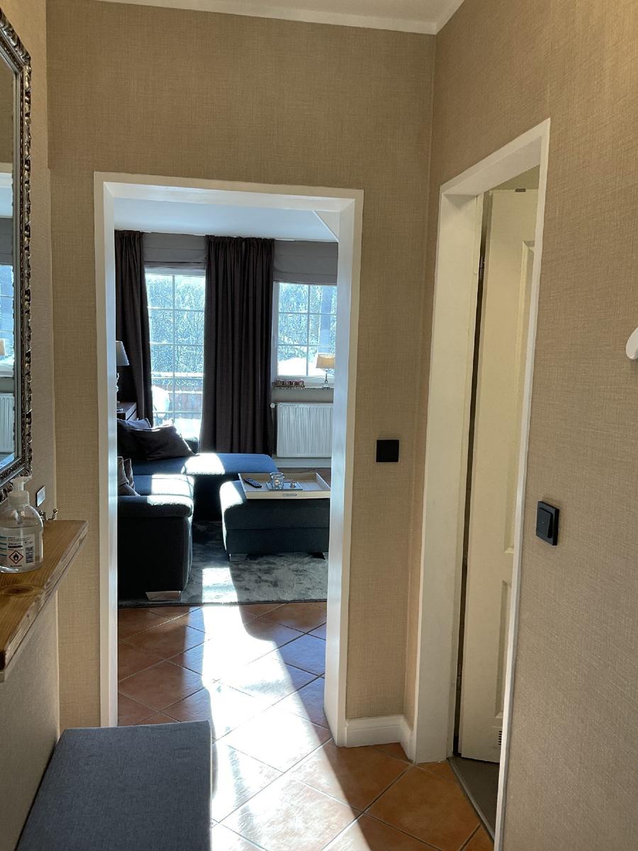 Durchgang mit Blick in Wohnzimmer mit Sofa und Fenstern.