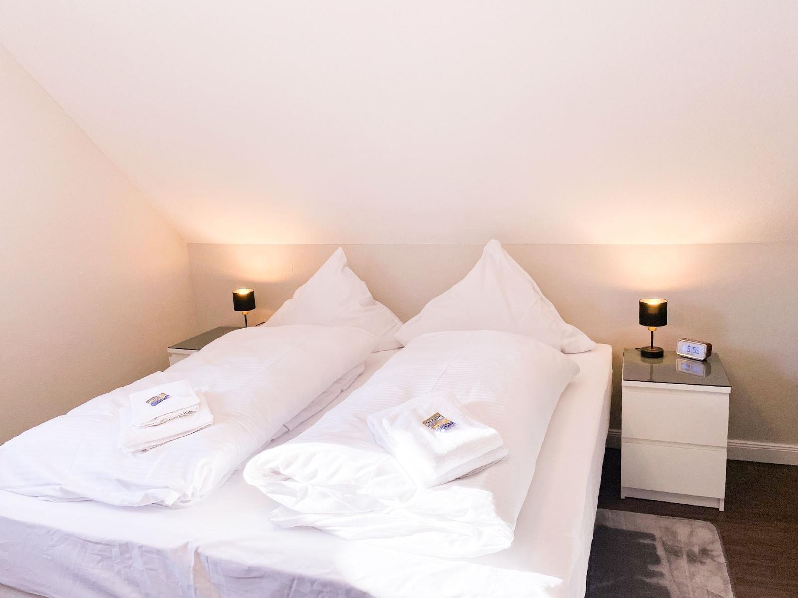 Schlafzimmer mit Doppelbett, zwei Nachttischen und Stehlampen.