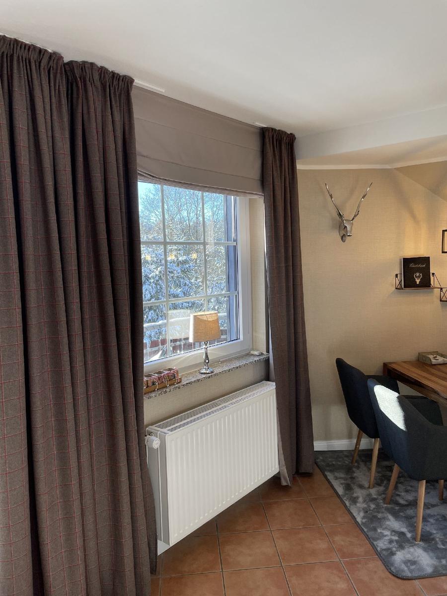 Raum mit Fenster, Vorhängen und Esstisch. Draußen Schnee. Wand mit Hirschgeweih.