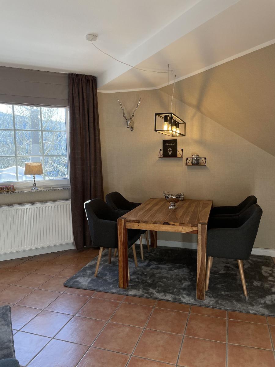 Esszimmer mit Holztisch, vier Stühlen und Fensterblick auf verschneite Landschaft.