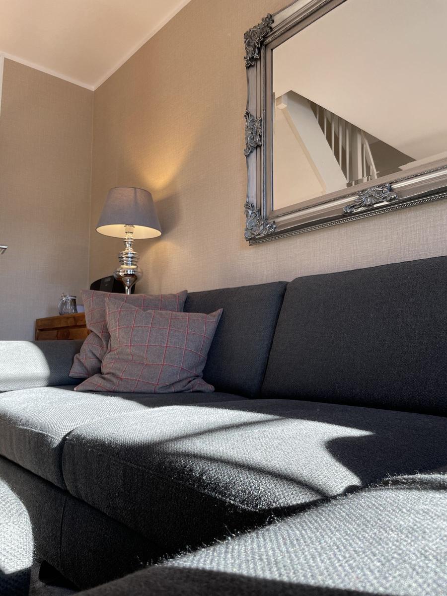 Ein Sofa mit Kissen und einem Spiegel an der Wand.