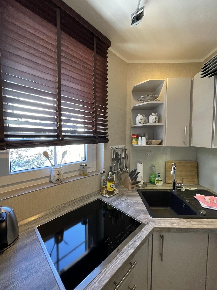 Küche mit Arbeitsfläche, Spüle, Herd und Fenster mit Jalousie.