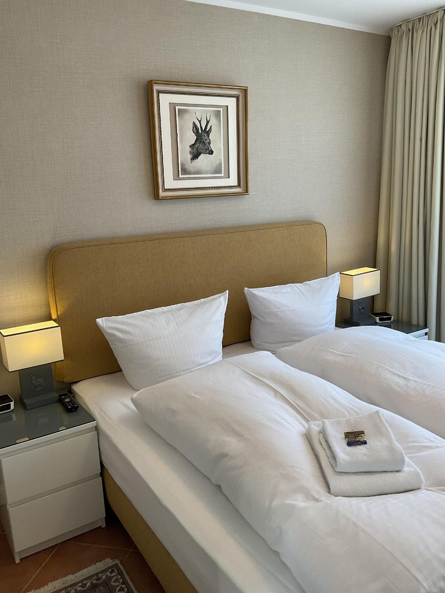 Schlafzimmer mit Doppelbett, Nachttischen und Bild an der Wand.