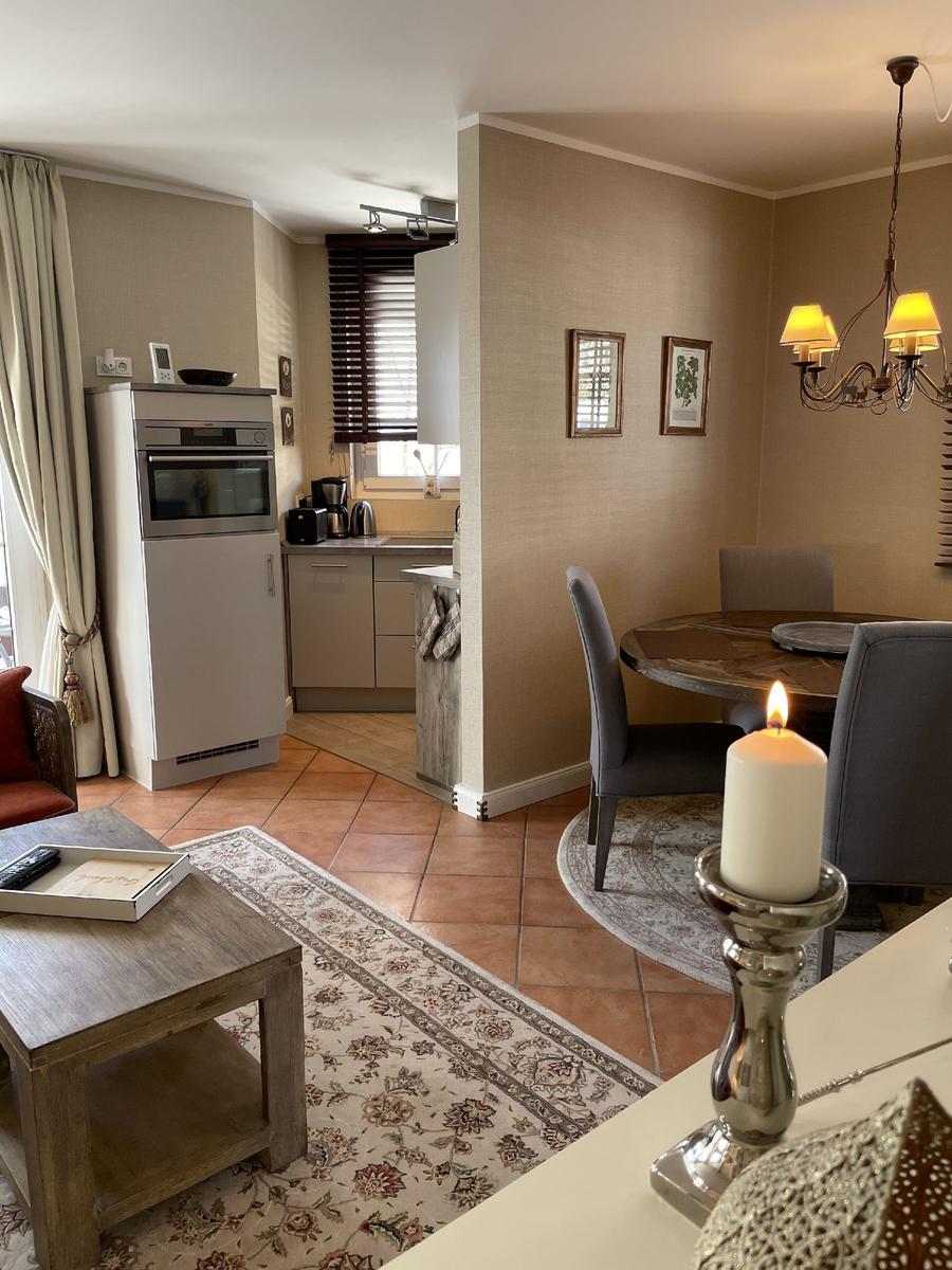 Wohn- und Essbereich mit Küchenzeile und Esstisch mit Kerze.