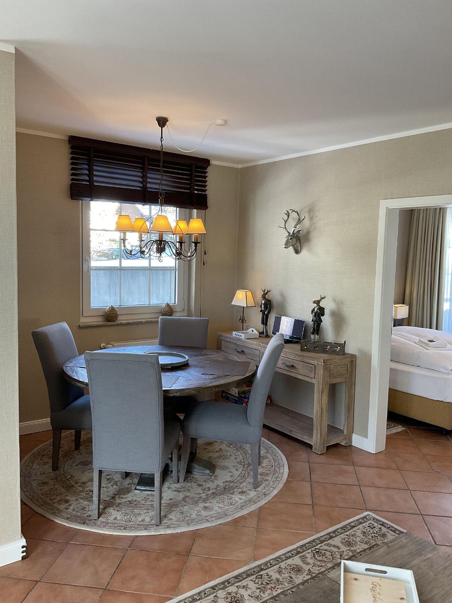 Esszimmer mit runden Tisch, grauen Stühlen und Deckenventilator. An der Wand hängt ein Hirschgeweih.