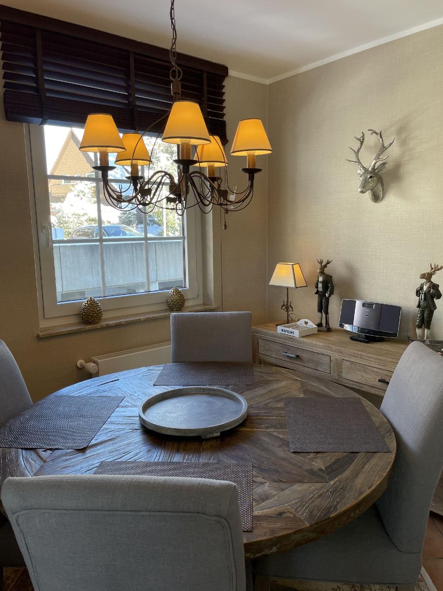 Rundes Esszimmer mit Holztisch, Stühlen und Deckenleuchte. Wanddekoration mit Hirschgeweih.