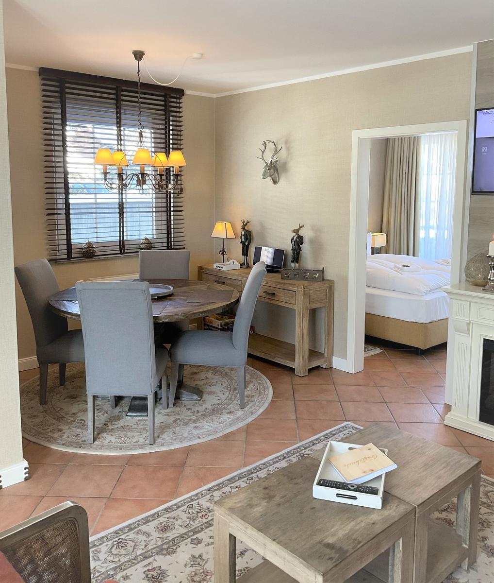 Essbereich mit Tisch und Stühlen, Wohnbereich mit Couchtisch und Blick in Schlafzimmer.