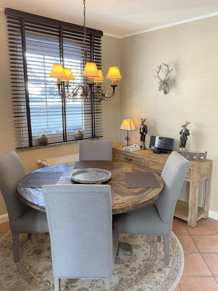 Rundes Esszimmer mit Holztisch, grauen Stühlen und dekorativen Hirschfiguren an der Wand.