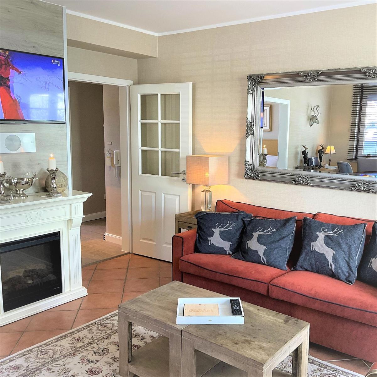 Ein Wohnzimmer mit rotem Sofa, Kamin und Fernseher.