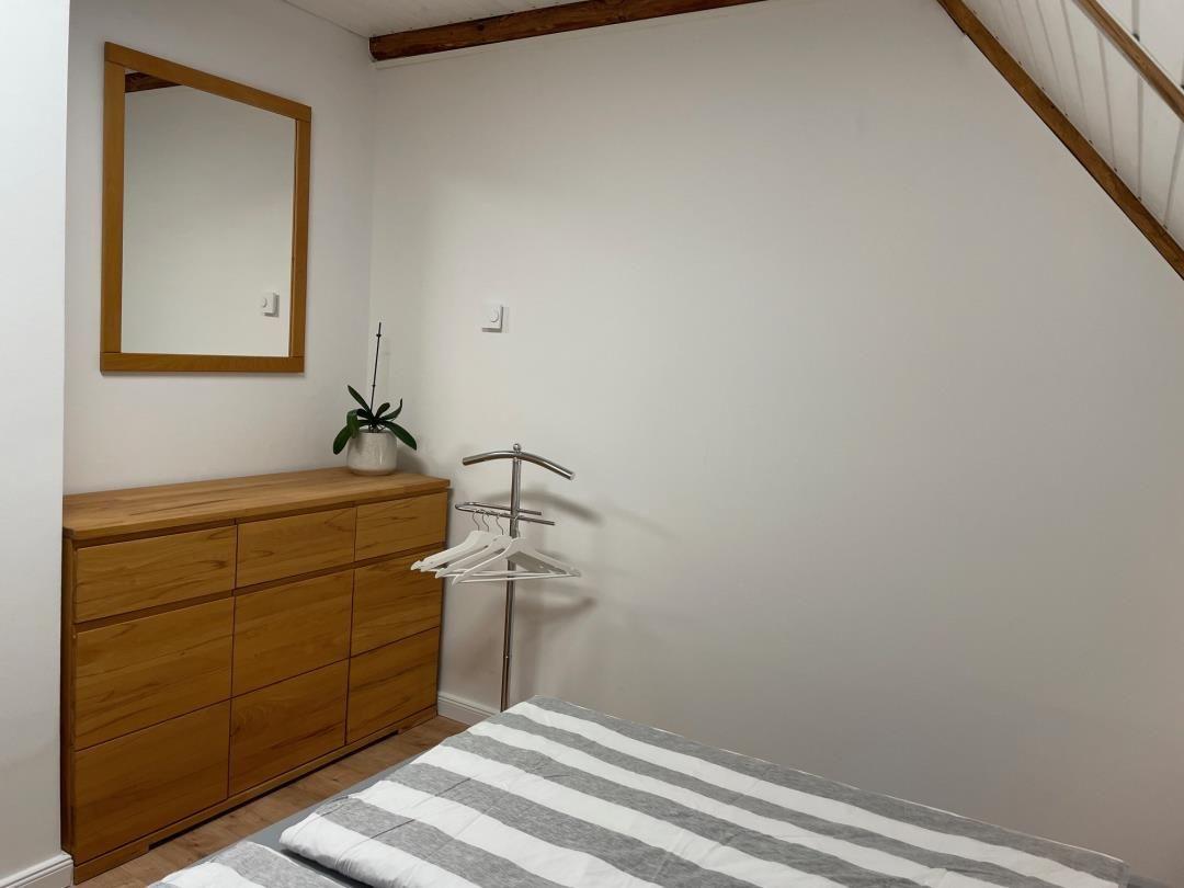 Schlafzimmer mit Bett, Kleiderschrank und Spiegel an der Wand.