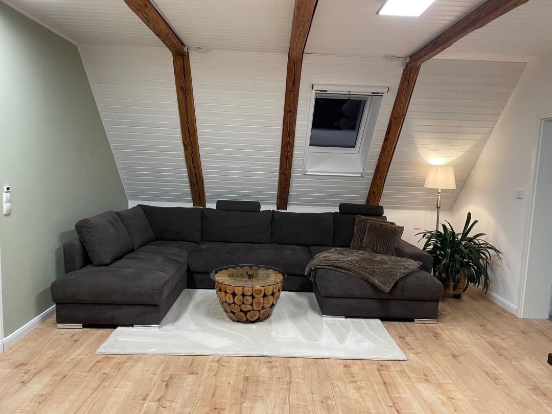 Wohnzimmer mit Ecksofa, Holzboden und Dachfenster.