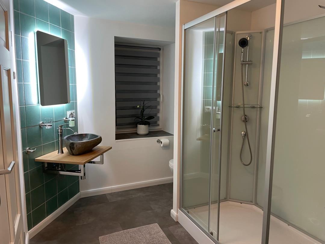 Badezimmer mit Dusche, Waschbecken und Fenster