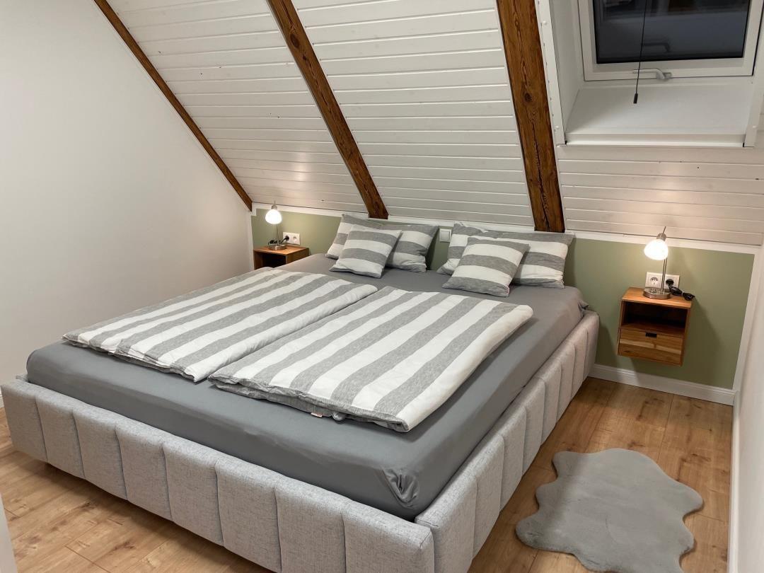 Schlafzimmer mit Doppelbett, Holzboden und schrägen Dachbalken.