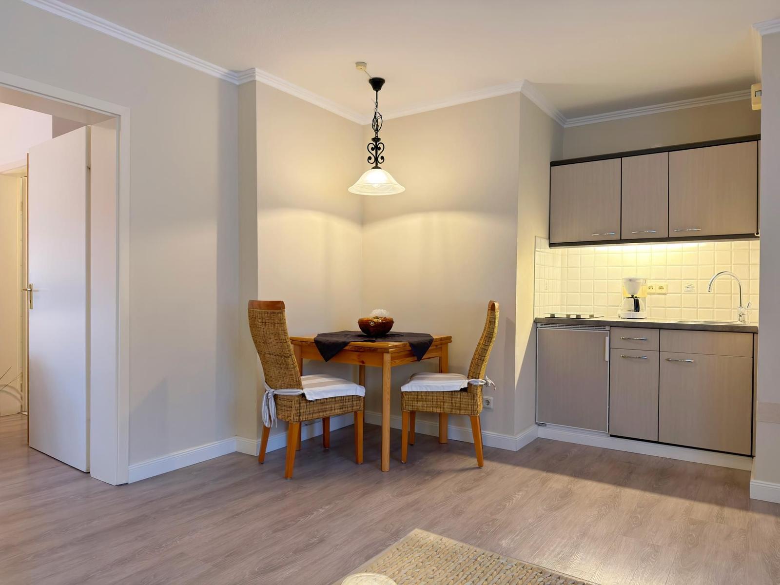 Küche mit Essbereich, Holztisch, zwei Stühle und integrierte Küchenschränke.