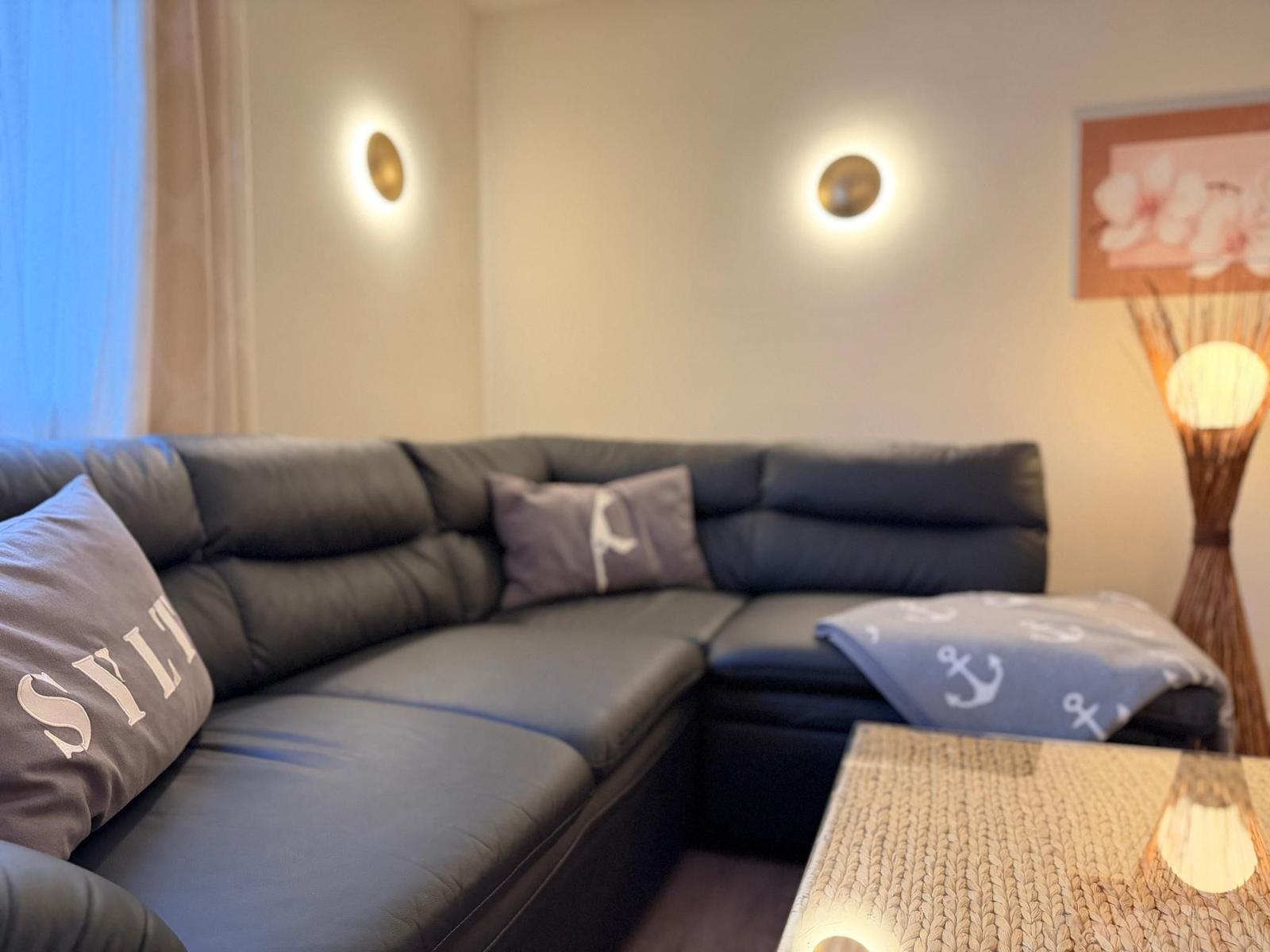 Ein Ecksofa mit Kissen und einer Decke mit Ankern liegt vor einem Tisch.