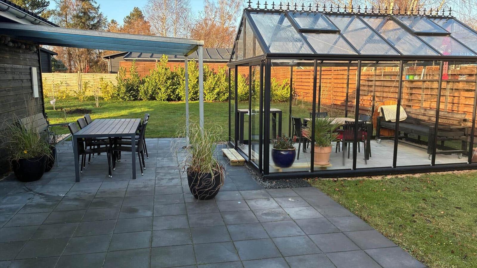 Terrace with seating and glass structure in the background.