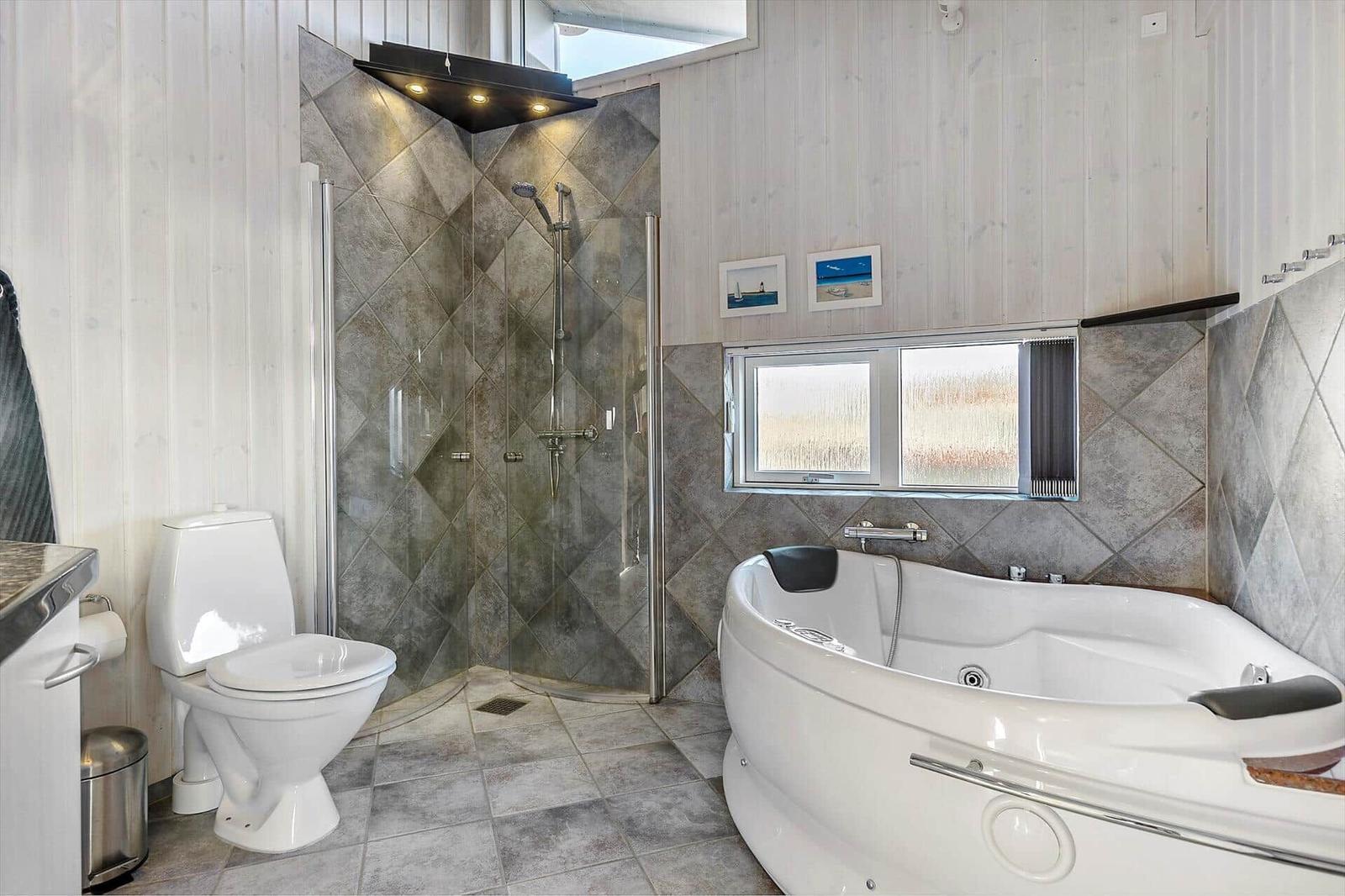 Bath with shower, bathtub, and toilet. Wooden walls and window with view.