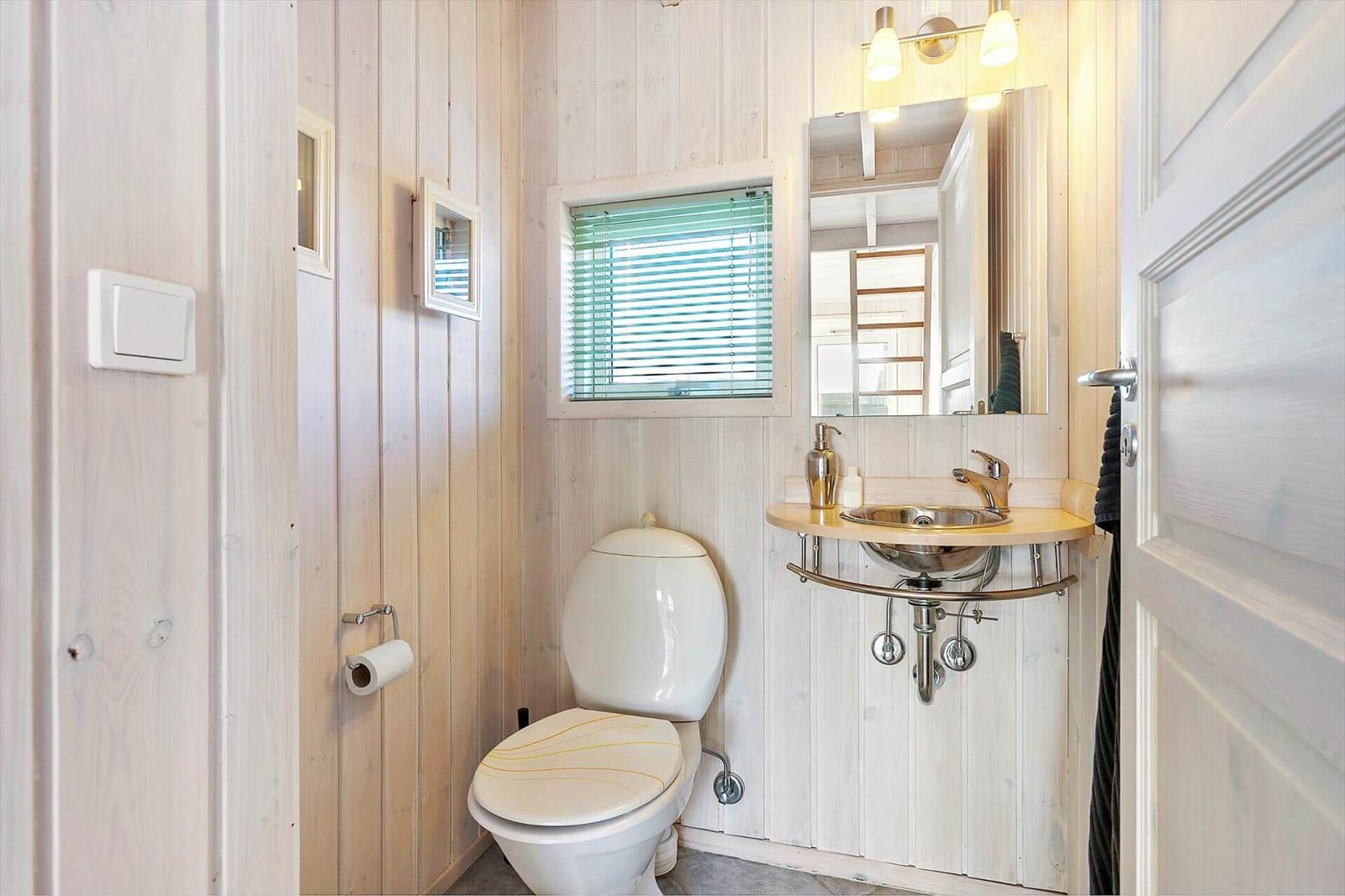 Bathroom with toilet, sink, and window with blinds.