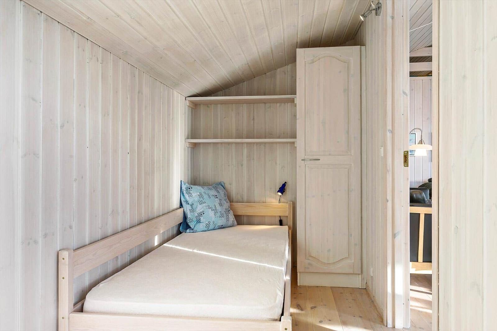 A bedroom with a bed, a shelf unit, and a wardrobe.