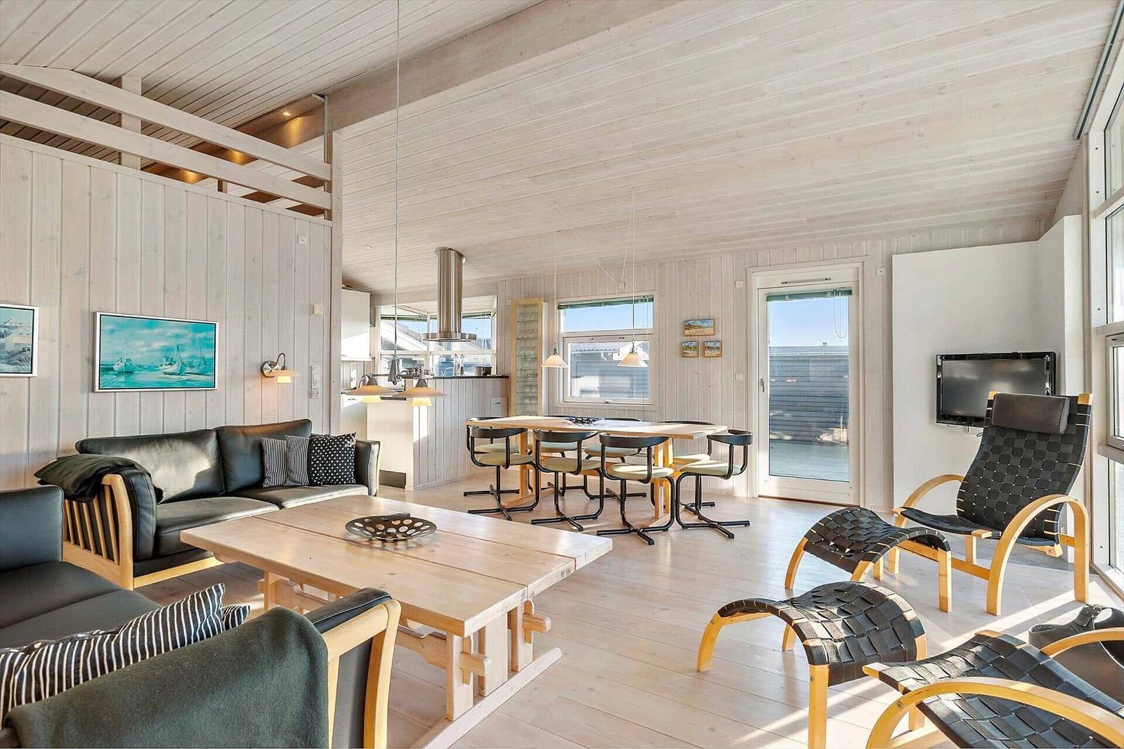 Living and dining area with wooden furniture and view to the terrace.