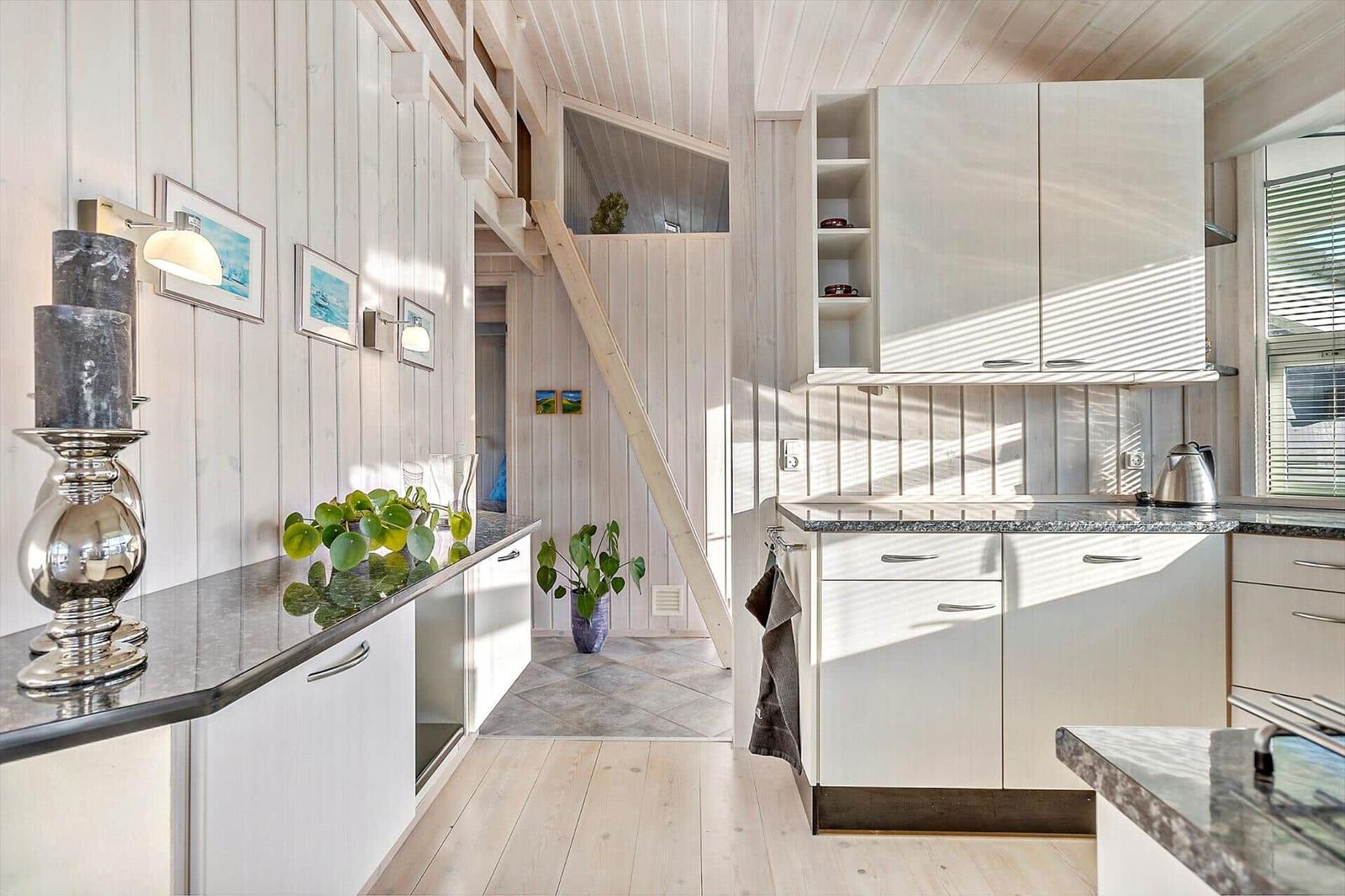 Kitchen with wooden walls, countertop, and staircase to upper level.