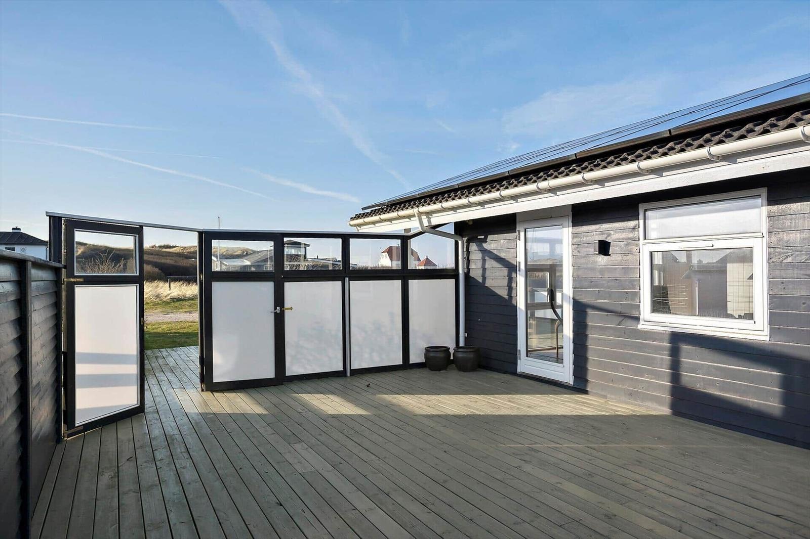Deck with wooden flooring and black mesh fence. Background shows a landscape with rooftops.