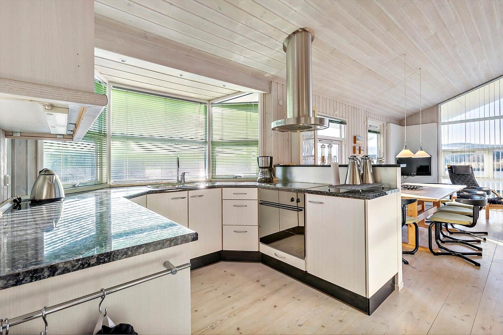 Kitchen with countertops, stove, and windows. Dining area with table and chairs.