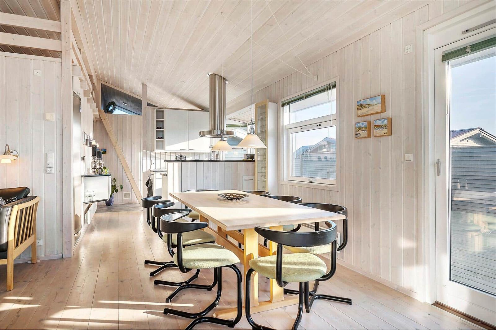 Dining area with table and chairs, kitchen, and window to outdoor terrace.
