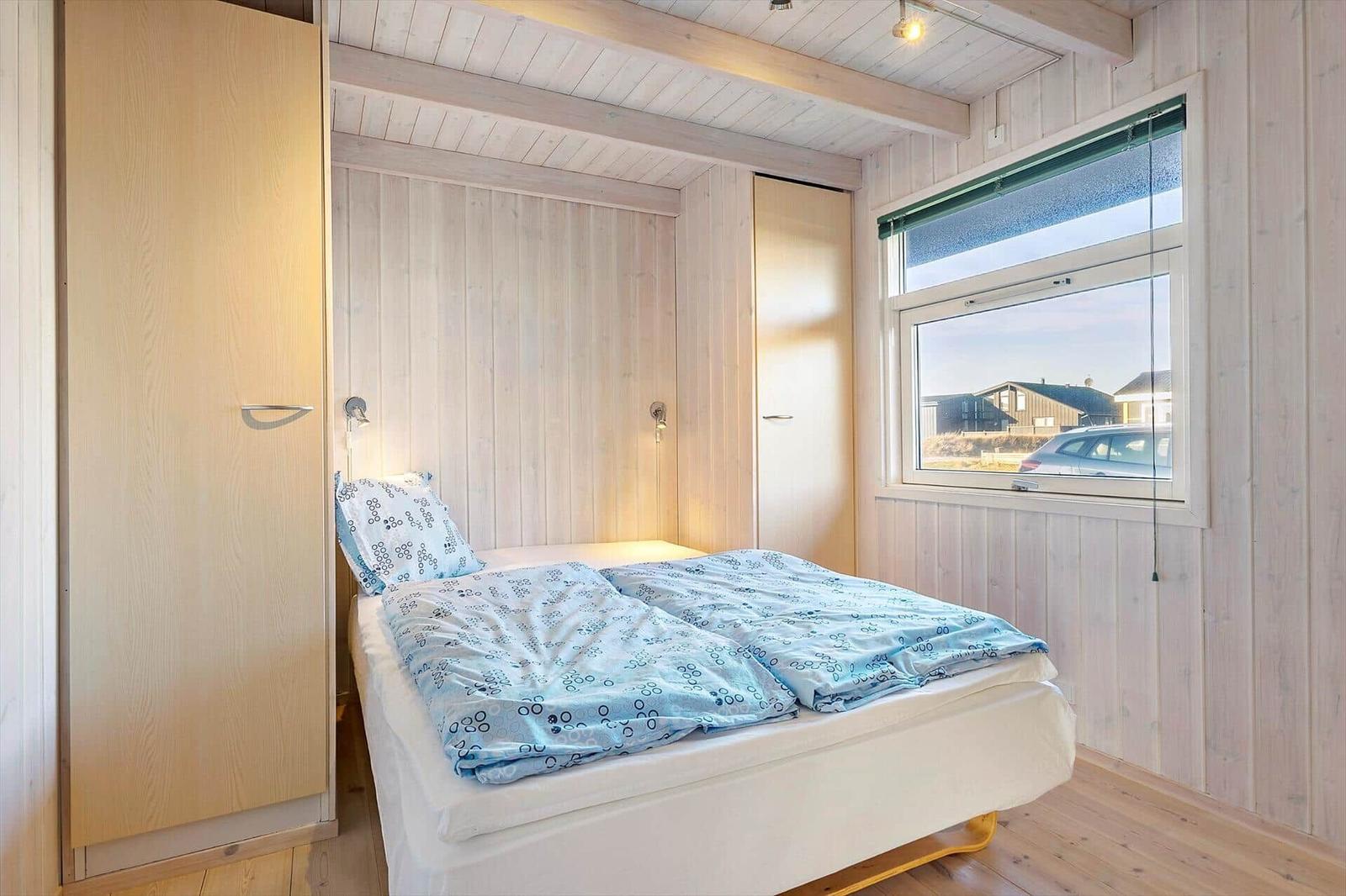 Bedroom with bed, wardrobe, and window overlooking outside.