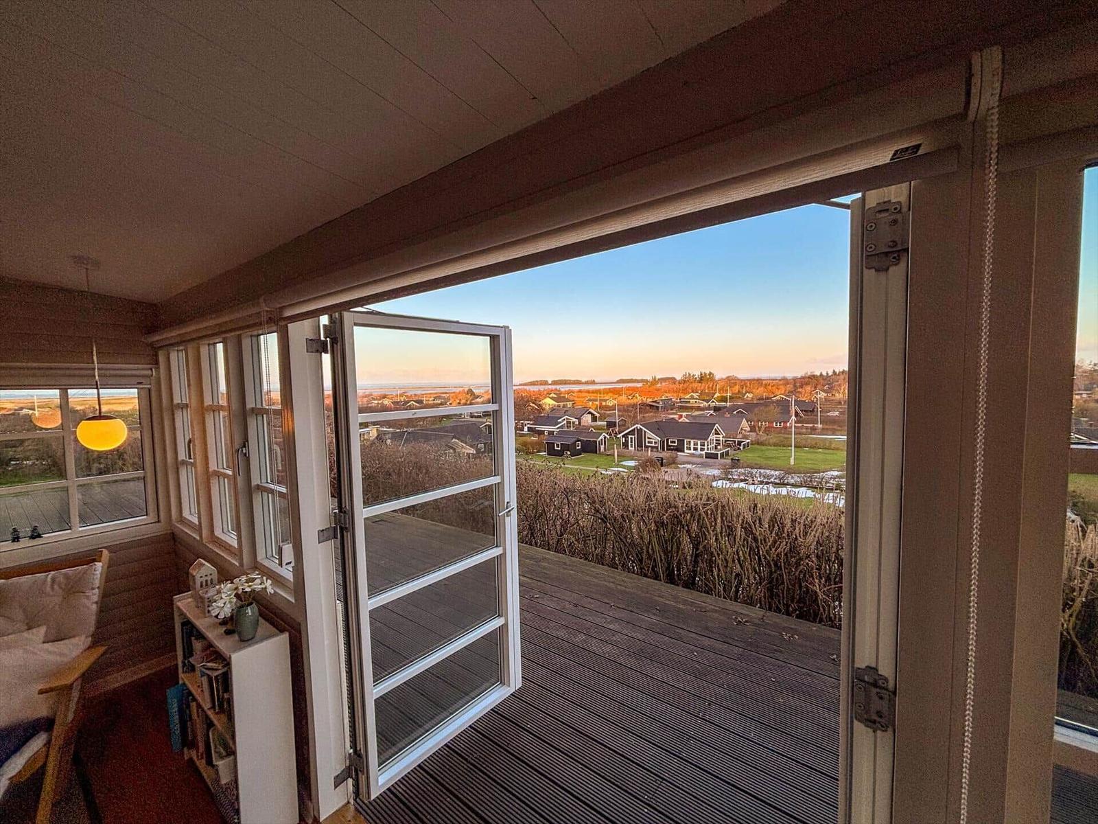 Durch die offene Tür blickt man auf eine Terrasse mit Blick auf Häuser und Landschaft.