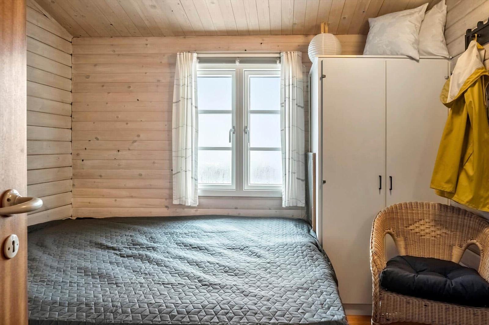 Schlafzimmer mit Holzwand, Bett, Schrank und Stuhl.