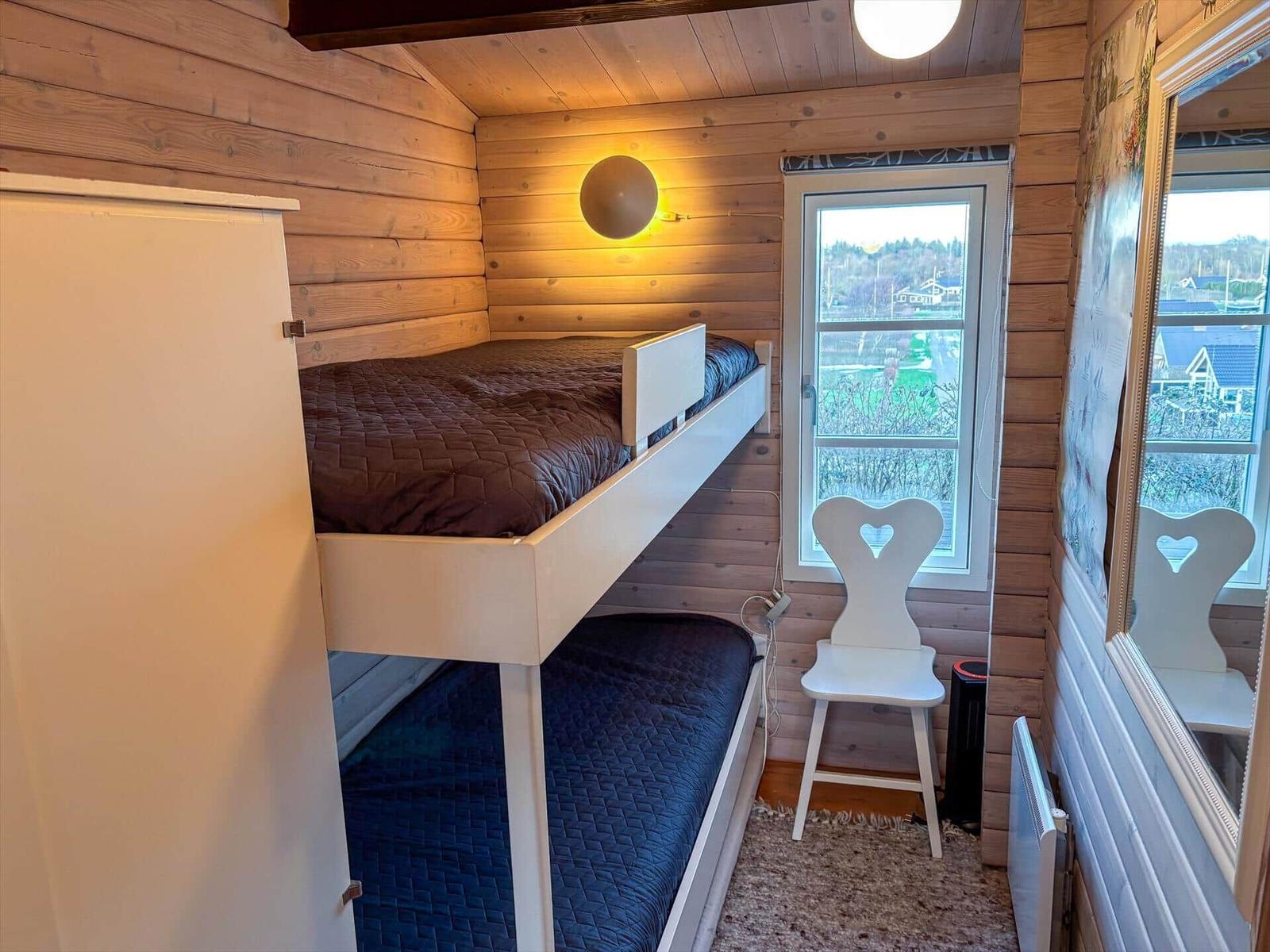 Ein Schlafzimmer mit Doppelstockbett, Fenster und Stuhl.