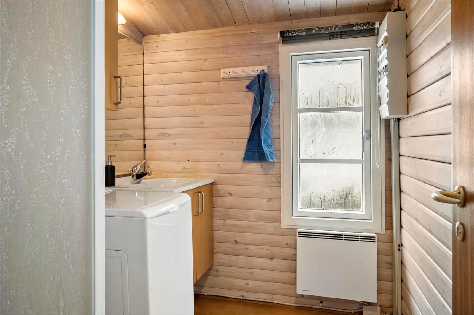 Badezimmer mit Waschmaschine, Spülung und Fenster.