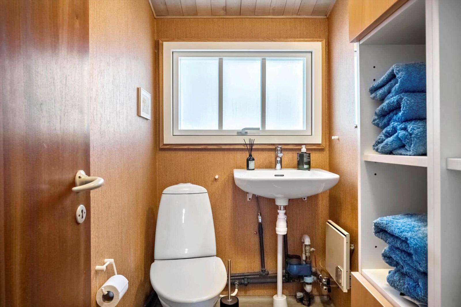 Badezimmer mit Toilette, Waschbecken und blauen Handtüchern.