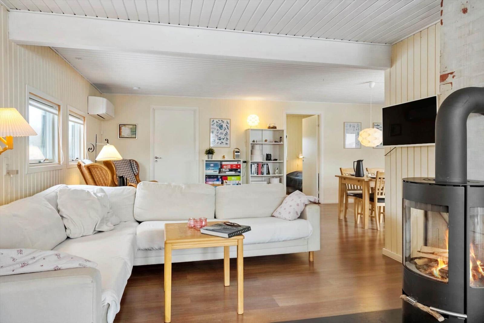 Wohnzimmer mit Sofa, Kamin und Essbereich. Holzboden und weiße Wände.