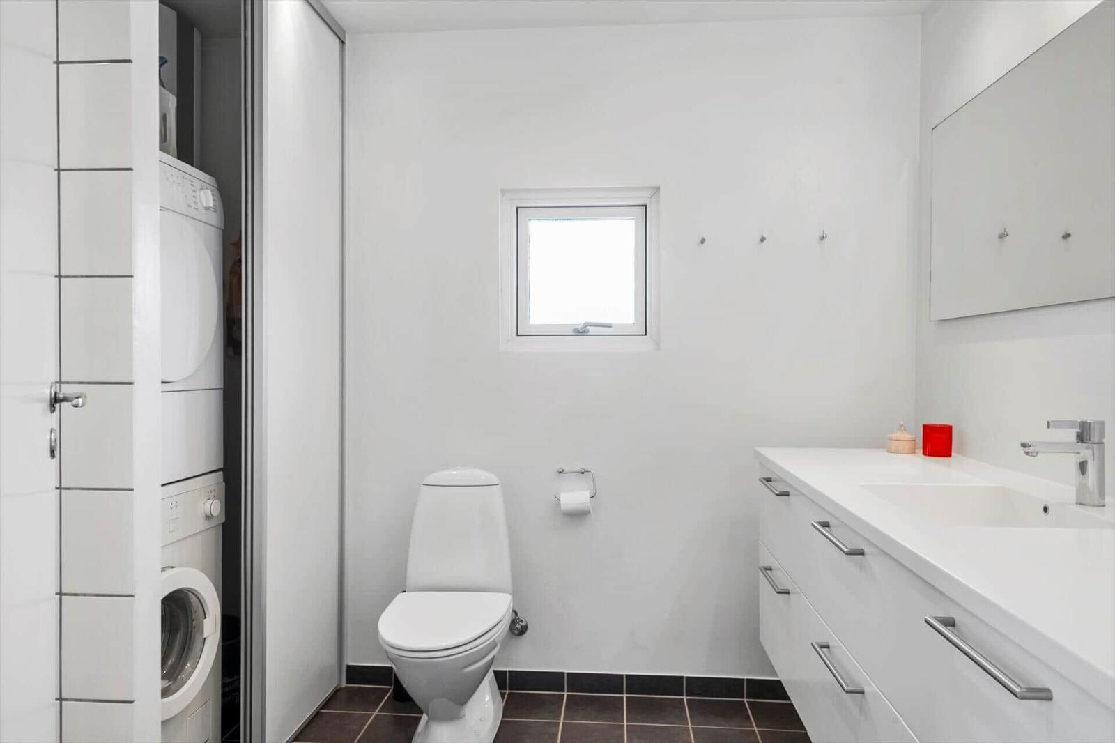 Badezimmer mit Toilette, Waschbecken und Waschmaschine